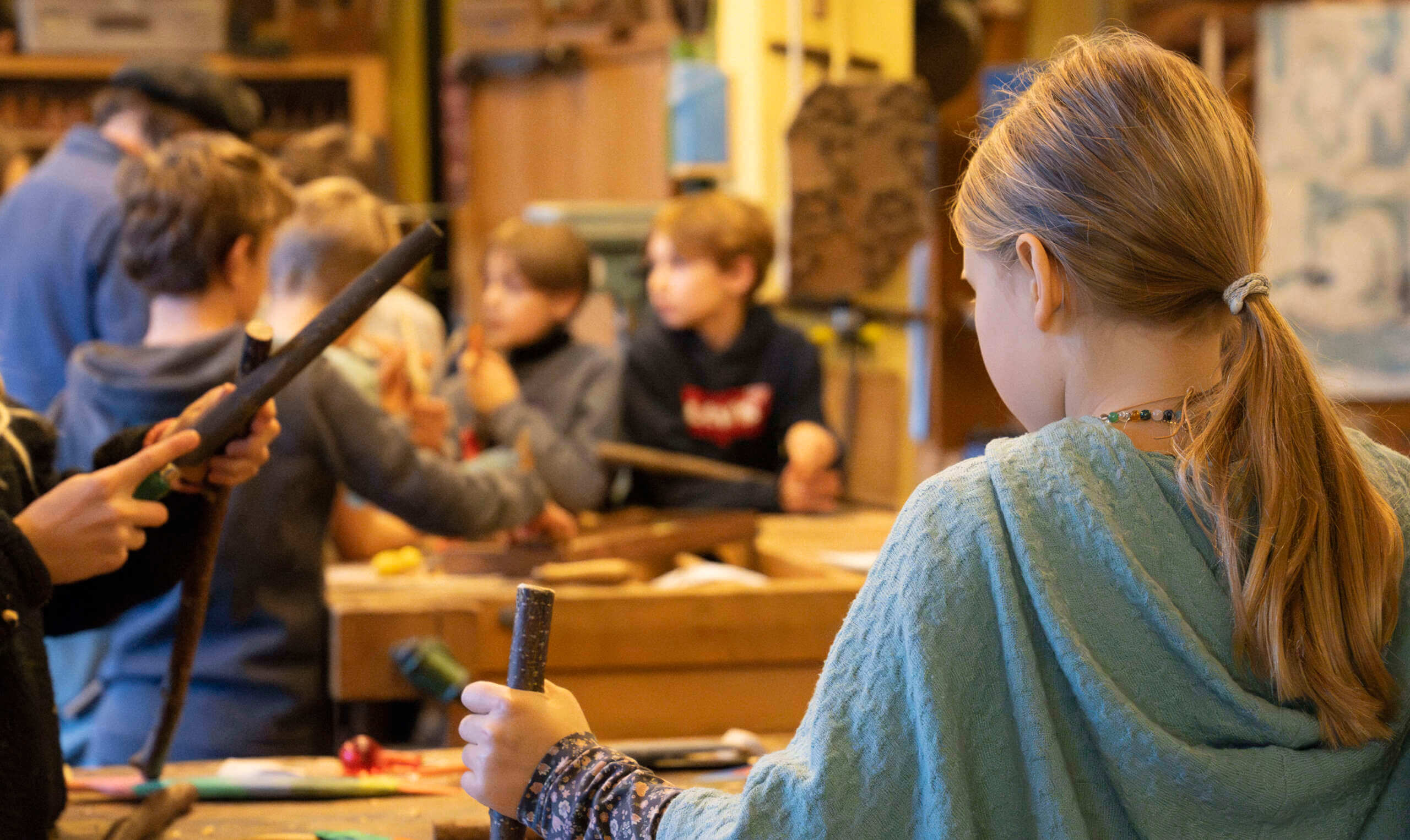 Unterricht im Werken an der Rudolf Steiner Schule Basel mit Unterstufenschülern, die dem Lehrer zusehen und einer Schülerin im Vordergrund